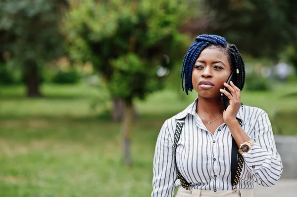 Şık Afro-Amerikan iş kadını askı ve bluz, pantolon, yarattığı açık ve konuşma üstünde hareket eden telefon.