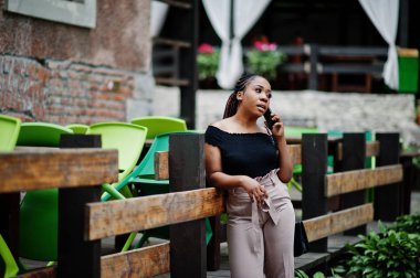 Şık Afrikalı-Amerikalı kadın açık ve kullanma cep telefonu poz verdi..