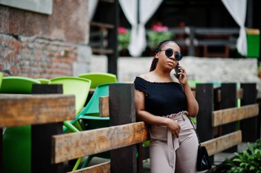 Şık Afrikalı-Amerikalı kadın açık ve kullanma cep telefonu poz verdi..