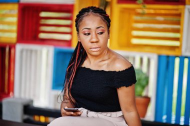 Şık Afrikalı-Amerikalı kadın açık ve kullanma cep telefonu poz verdi..