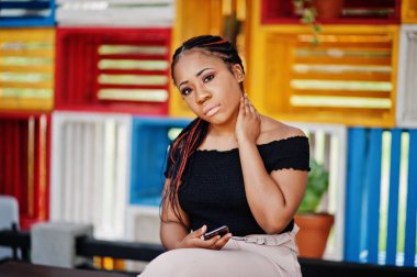 Şık Afrikalı-Amerikalı kadın açık ve kullanma cep telefonu poz verdi..