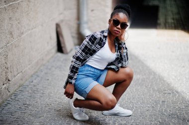 Hip hop Afro-Amerikan Kız güneş gözlüğü ve kot şort. Siyah kadın portresi rahat sokak moda.