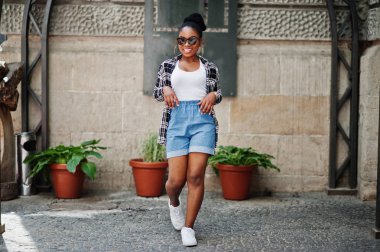 Hip hop Afro-Amerikan Kız güneş gözlüğü ve kot şort. Siyah kadın portresi rahat sokak moda.
