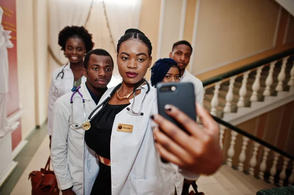 Group of african doctors students inside medical university making selfie at phone.