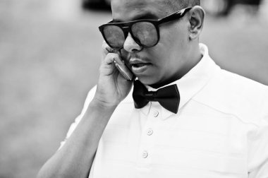 Yakın güneş gözlüğü ve papyon şık Arap adam portresi oluşturuyordu açık ve üstünde hareket eden telefon konuşma. Arap modeli çocuk.