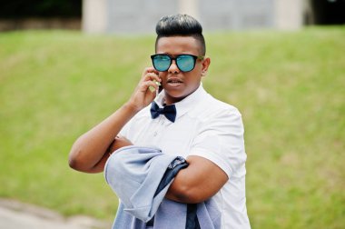 Yakın güneş gözlüğü ve papyon şık Arap adam portresi oluşturuyordu açık ve üstünde hareket eden telefon konuşma. Arap modeli çocuk.