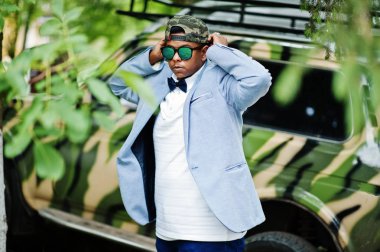 Güneş gözlüğü, şapka ve papyon şık Arap adama karşı askeri araç poz verdi. Arap modeli çocuk.