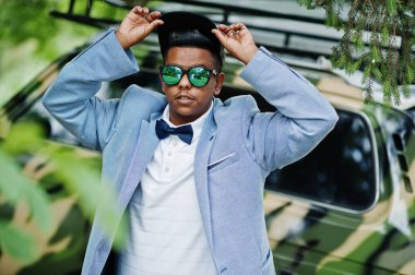 Güneş gözlüğü, şapka ve papyon şık Arap adama karşı askeri araç poz verdi. Arap modeli çocuk.