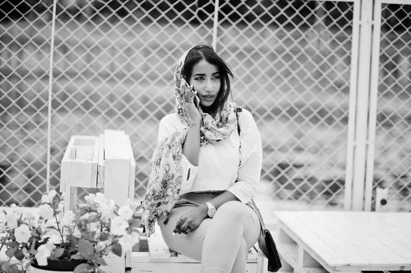 Beyaz bluz ve şeftali pantolon Arap kız moda açık poz verdi. Cep telefonunda bir şık Müslüman kadın.