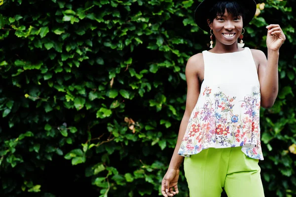 İnanılmaz bir Afro-Amerikan modeli kadın yeşil pantolon ve siyah şapka Park'ta farklı duygular ile poz verdi. 