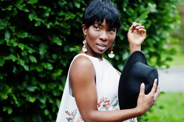 İnanılmaz bir Afro-Amerikan modeli kadın yeşil pantolon ve siyah şapka Park'ta farklı duygular ile poz verdi. 