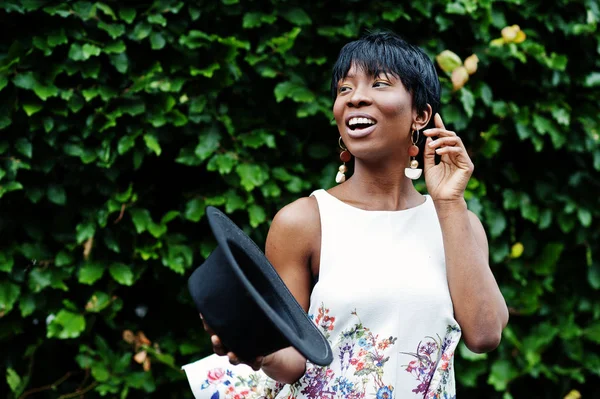 İnanılmaz bir Afro-Amerikan modeli kadın yeşil pantolon ve siyah şapka Park'ta farklı duygular ile poz verdi. 