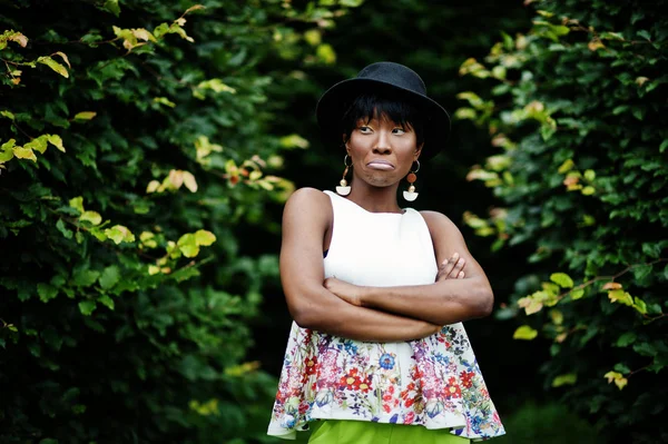 Afro-Amerikan model kadın yeşil pantolon ve siyah şapka Park, farklı duygular ile poz verdi şaşırtıcı gösterir üzgün yüz.