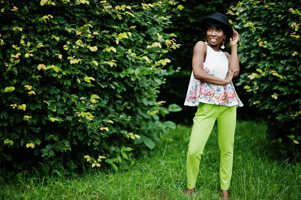 惊人的非洲裔美国模特在绿色的裤子和黑色的帽子摆在公园 — 图库照片