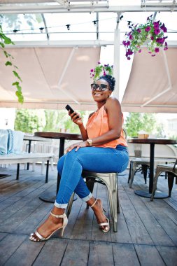 Caffe cep telefonu ile masada oturan Afro-Amerikan Kız.