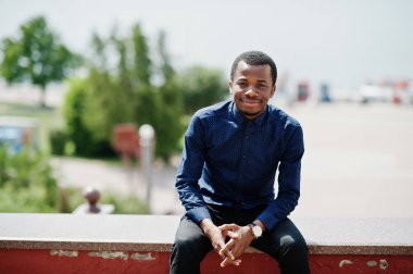 Afrika adam Street şehir giyim mavi gömlek ve siyah pantolon poz verdi.