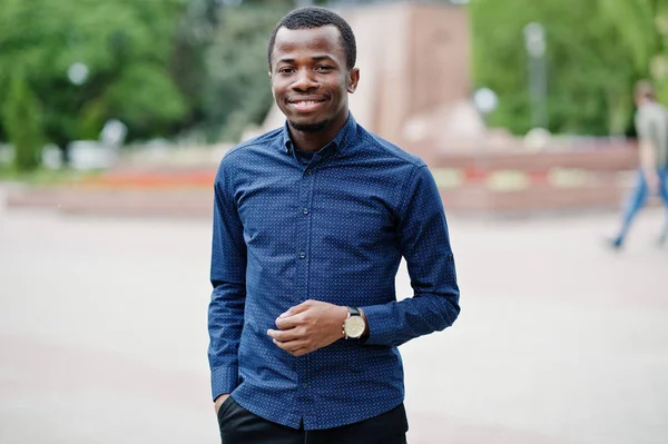 African  man posed at street of city wear on blue shirt and black pants.