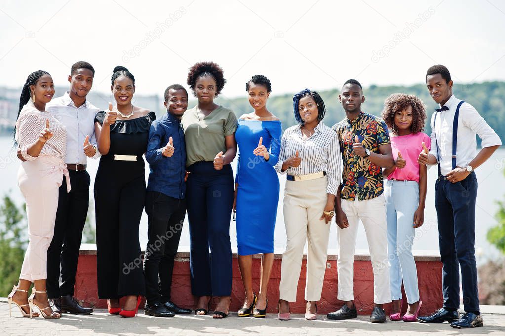 Group of ten african american people posed at street of city. Fashionable people of Africa shows thumb up.