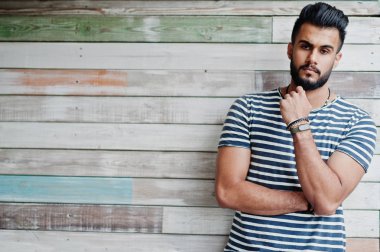 Yakışıklı uzun boylu Arap sakal man modeli soyulmuş gömlek, ahşap arka plan açık poz verdi. Moda Arap adam. 