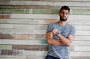 Yakışıklı uzun boylu Arap sakal man modeli soyulmuş gömlek, ahşap arka plan açık poz verdi. Moda Arap adam. 