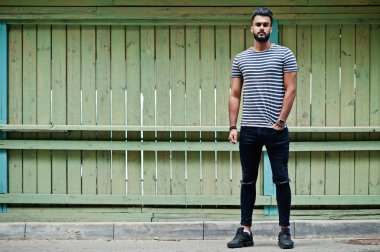 Yakışıklı uzun boylu Arap sakal man modeli soyulmuş gömlek, ahşap arka plan açık poz verdi. Moda Arap adam. 