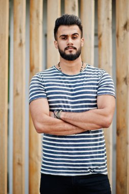 Yakışıklı uzun boylu Arap sakal man modeli soyulmuş gömlek, ahşap arka plan açık poz verdi. Moda Arap adam. 