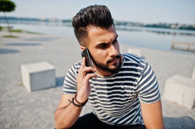 Yakışıklı uzun boylu Arap sakal man modeli soyulmuş gömlek, açık poz verdi. Cep telefonu ile moda Arap adam.