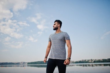 Yakışıklı uzun boylu Arap sakal man modeli soyulmuş gömlek, göl ve gökyüzü karşı açık poz verdi. Moda Arap adam. 