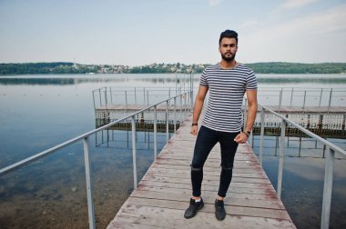 Yakışıklı uzun boylu Arap sakal man modeli soyulmuş gömlek, göl iskelede açık poz verdi. Moda Arap adam. 