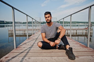 Yakışıklı uzun boylu Arap sakal man modeli soyulmuş gömlek, göl iskelede açık poz verdi. Moda Arap adam. 