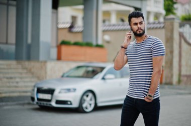 Yakışıklı uzun boylu Arap sakal man modeli soyulmuş gömlek, araba karşı açık poz verdi. Moda Arap adam. Müslüman işadamı cep telefonu konuşma.