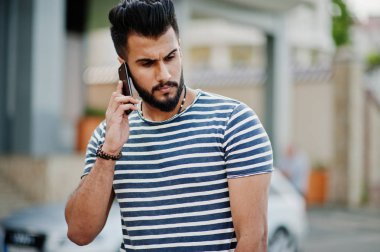 Yakışıklı uzun boylu Arap sakal man modeli soyulmuş gömlek, araba karşı açık poz verdi. Moda Arap adam. Müslüman işadamı cep telefonu konuşma.