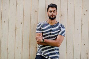 Yakışıklı uzun boylu Arap sakal man modeli soyulmuş gömlek, ahşap arka plan açık poz verdi. Moda Arap adam. 