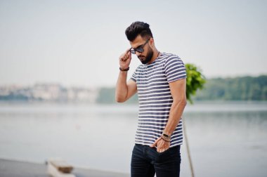 Yakışıklı uzun boylu Arap sakal man modeli soyulmuş gömlek, açık poz verdi. Güneş gözlüğü moda Arap adama.