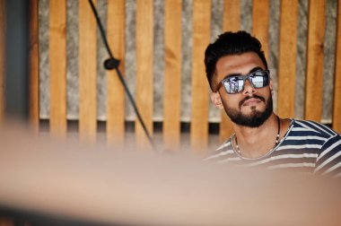 Yakışıklı uzun boylu Arap sakal man modeli soyulmuş gömlek, açık poz verdi. Güneş gözlüğü moda Arap adama.