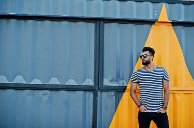 Yakışıklı uzun boylu Arap sakal man modeli soyulmuş gömlek, açık poz verdi. Sarı boyalı duvar karşı güneş gözlüğü moda Arap adama.