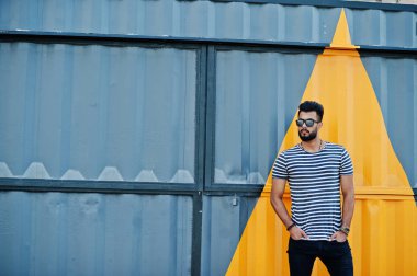 Yakışıklı uzun boylu Arap sakal man modeli soyulmuş gömlek, açık poz verdi. Sarı boyalı duvar karşı güneş gözlüğü moda Arap adama.