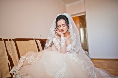 Kanepede kapalı oturan güzel beyaz gelinlik içinde bir gelin portresi.