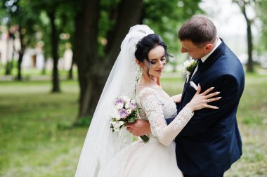 Güzel ve mutlu yeni evli çift ayakta yeşil park onların düğün günü.