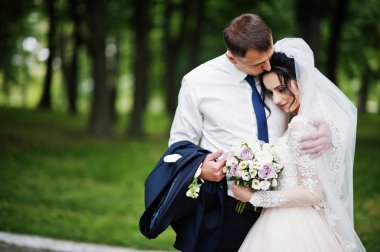 Güzel ve mutlu yeni evli çift ayakta yeşil park onların düğün günü.