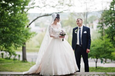 Güzel ve mutlu yeni evli çift ayakta yeşil park onların düğün günü.