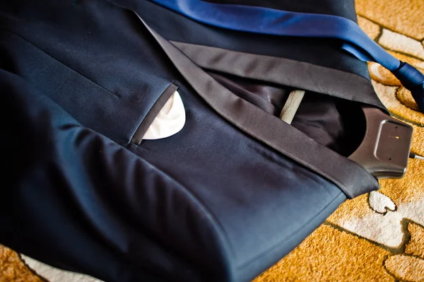 Close-up photo of a groom's suit or tuxedo on the hanger laying in the floor.