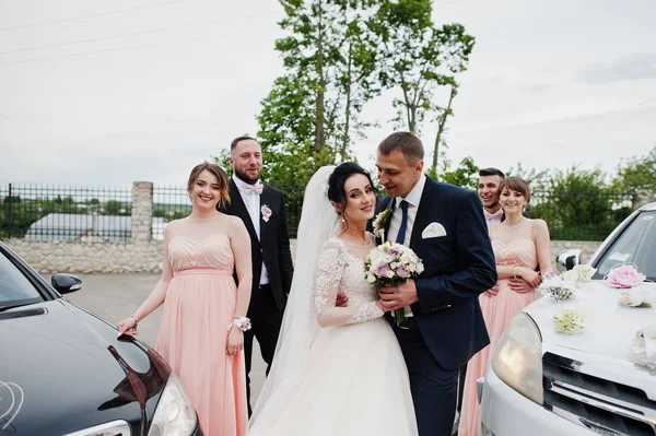Hochzeitspaar Und Trauzeugen Mit Brautjungfern Posieren Zwischen Zwei Geschmückten Hochzeitsautos — Stockfoto