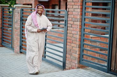 Orta Doğu Arap adam elinde tablet ile modern bina karşı sokağında poz verdi.