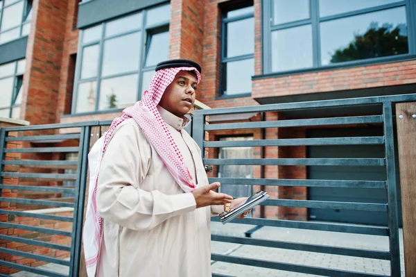 Orta Doğu Arap adam elinde tablet ile modern bina karşı sokağında poz verdi.