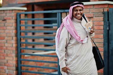 Orta Doğu Arap iş adamı siyah çanta ve euro paralar ile modern bina karşı sokağında poz verdi.