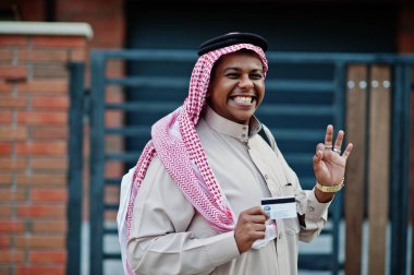 Orta Doğu Arap iş adamı siyah çanta ve kredi kartı el ile modern bina karşı sokağında poz verdi.