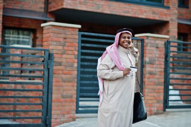 Orta Doğu Arap iş adamı siyah çanta ve kredi kartı el ile modern bina karşı sokağında poz verdi.