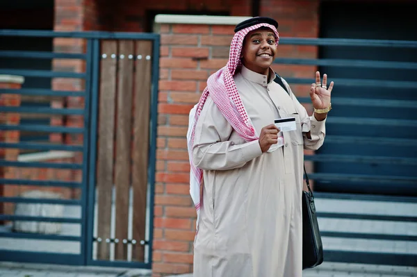 Orta Doğu Arap iş adamı siyah çanta ve kredi kartı el ile modern bina karşı sokağında poz verdi.