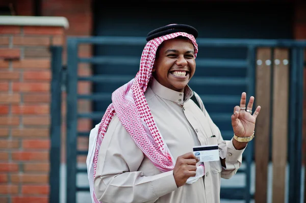 Orta Doğu Arap iş adamı siyah çanta ve kredi kartı el ile modern bina karşı sokağında poz verdi.